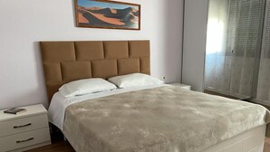 A bedroom with a large bed, a headboard, a bedside table, and a nightstand. - Great value for its price (Tirana)