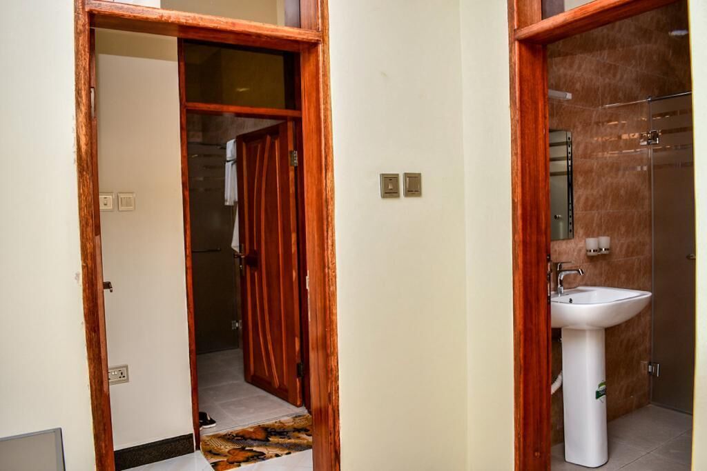 A bathroom with a wooden door, a white sink, and a mirror.