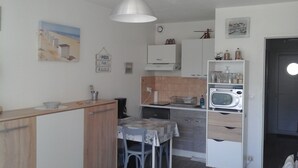 Una cocina compacta con microondas, una pequeña mesa de comedor y un armario.