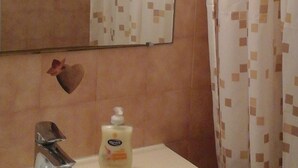 Un baño con lavamanos, espejo y cortina de ducha con diseño geométrico.