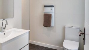 Un baño con un lavamanos blanco, toallero y un inodoro.