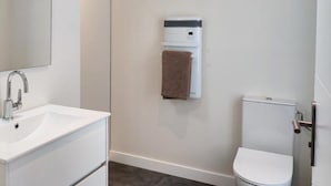 Ein Badezimmer mit einem weißen Waschbecken, einem Handtuchhalter und einer Toilette.