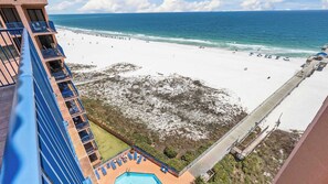 A high-rise hotel with a pool, beach view, and a pier extending into the ocean.