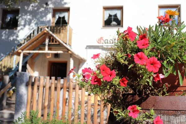 A building with a wooden staircase, a wooden fence, and a sign that reads "Gasthof".