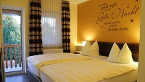 A hotel room with a bed, a nightstand, a lamp, and a window with curtains. - Gasthaus Pension Augenstein (Winzer)