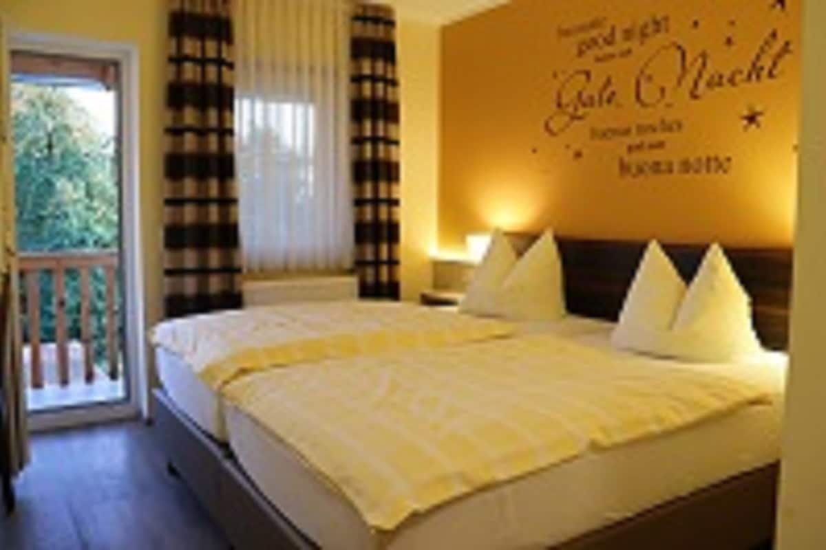 A hotel room with a bed, a nightstand, a lamp, and a window with curtains.