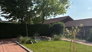 A paved pathway leading to a well-maintained lawn with a small tree and a rock garden. - Gasthaus Pension Augenstein (Winzer)