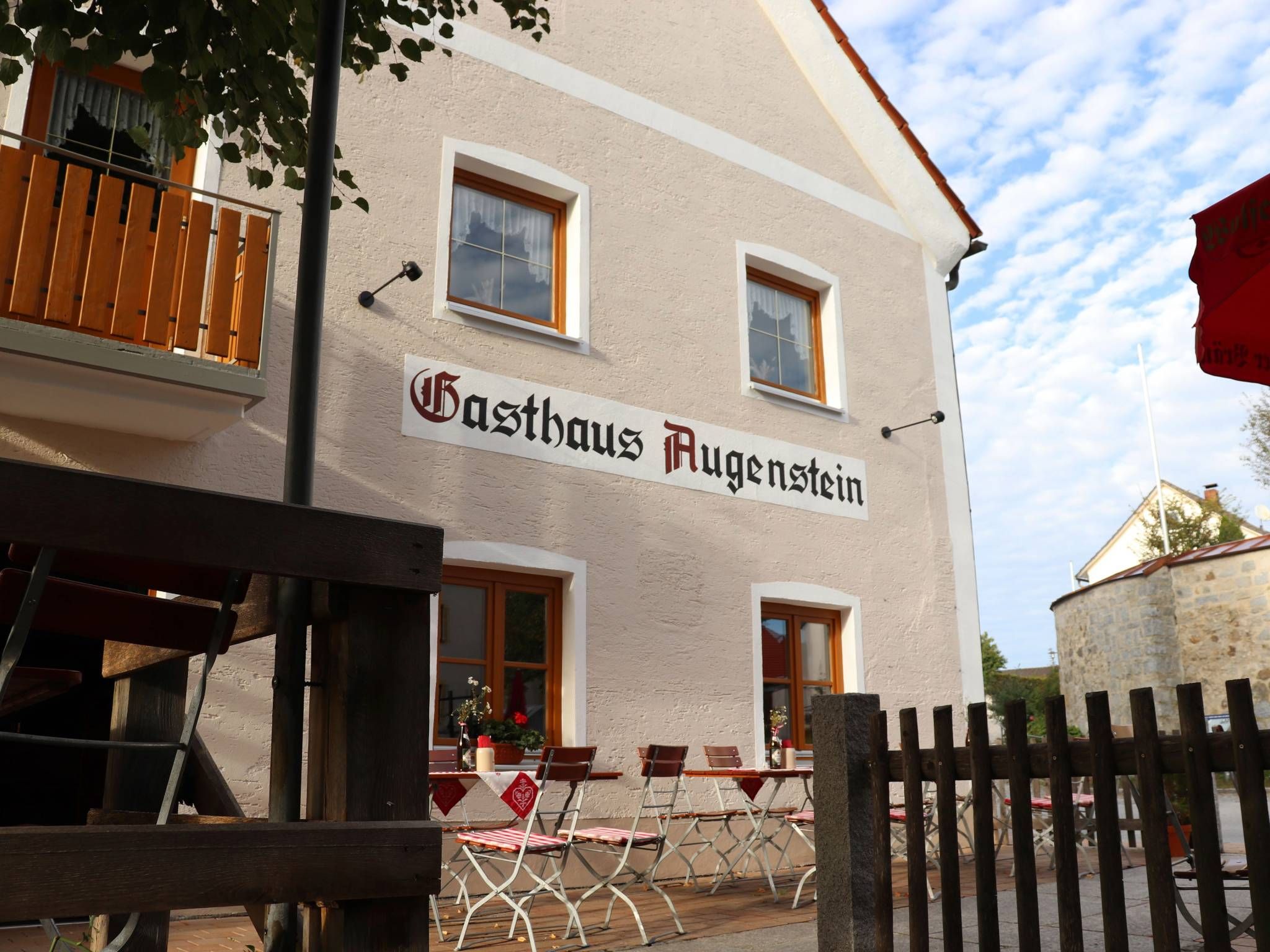 Un bâtiment sur lequel on peut lire l’inscription « Gasthaus Augenstein », avec une terrasse aménagée avec des tables et des chaises.