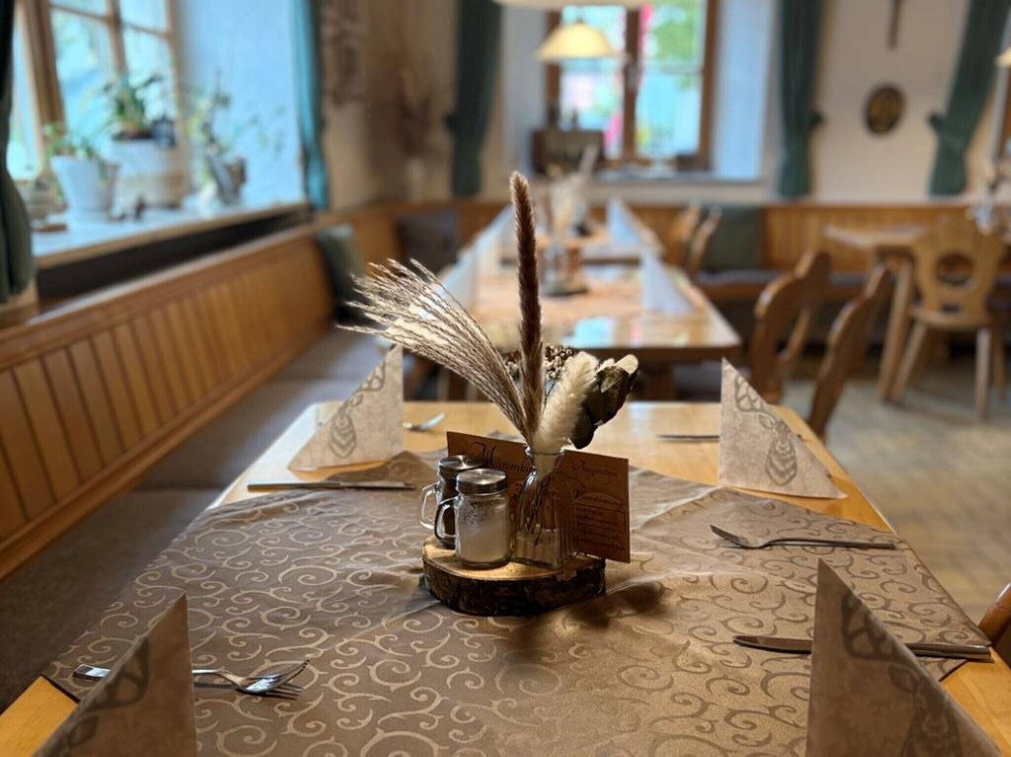 Ein Esstisch mit einer gemusterten Tischdecke, einer Karaffe und dekorativen Gegenständen.
