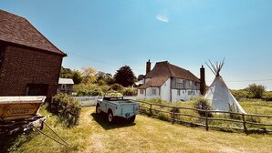 A rural setting with a white house, a wooden fence, and a white teepee. - A Unique Tudor Manor House dating from 1547 (Painters Forstal)