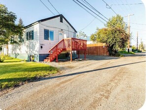 A single-story house with a red staircase leading to a covered porch. - Large Govt hill studio-near  downtown (Anchorage)