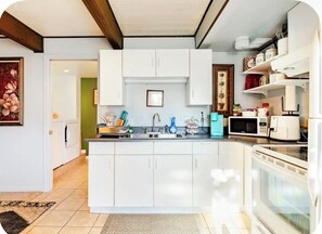 A modern kitchen with white cabinets, a central island, a microwave, and a coffee maker.