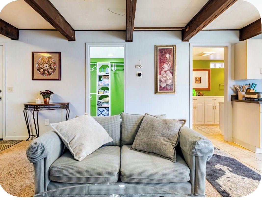 A living room with a sofa, a small table with a vase, and a framed picture on the wall.