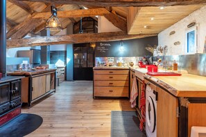 A rustic kitchen with wooden floors, a central island, and a hanging light fixture.