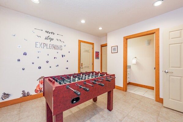 A room with a foosball table, a wall with animal stickers, and a motivational quote.