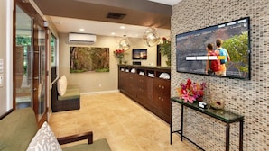 A modern living room with a TV, sofa, and decorative plants.