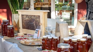 A display table with jars of honey and a beehive in the background.