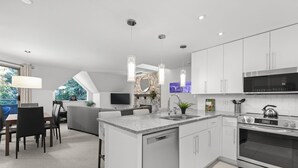 A modern kitchen with white cabinetry, a built-in oven, and a granite countertop.