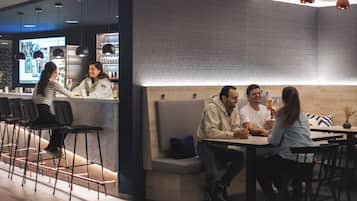 Un área de bar moderna con asientos, una barra y lámparas colgantes.