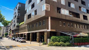 A multi-story hotel with a modern facade, large windows, and a visible entrance with a covered area. - Sunlight - 150m From the Lake (Lugano)