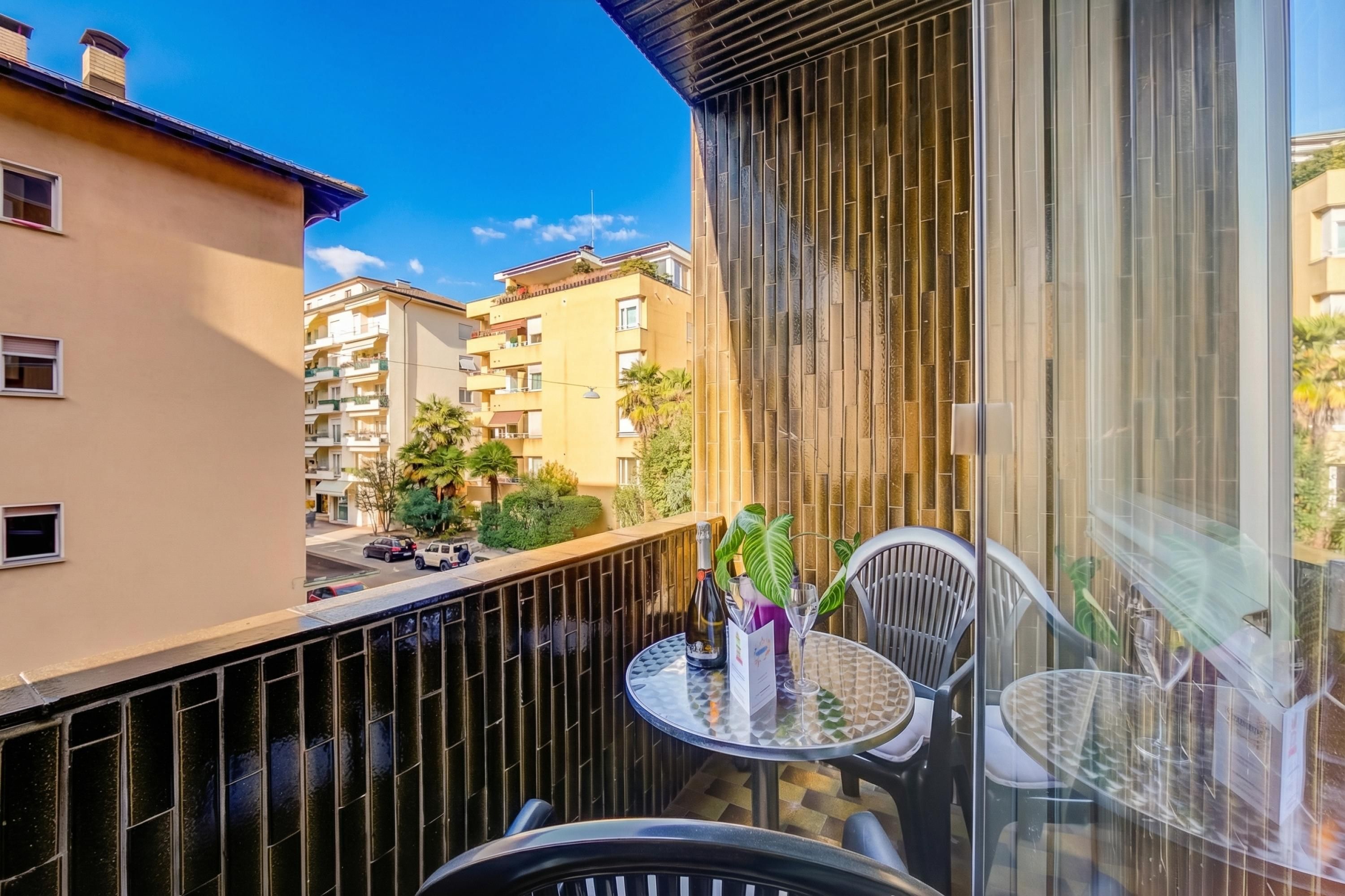 Un balcone con tavolo, sedie e una bottiglia di champagne.