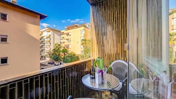Un balcone con tavolo, sedie e una bottiglia di champagne.