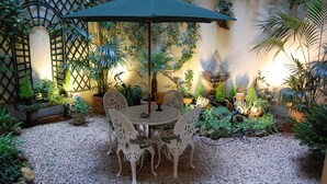 A patio area with a round table and chairs, surrounded by potted plants and a decorative fence. - Port Royal Hotel (Paris)