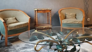 A room with two armchairs, a small wooden table, and two framed paintings on the wall. - Port Royal Hotel (Paris)