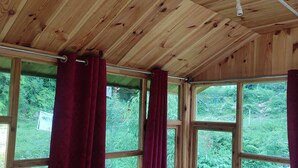 A room with wooden ceiling and large windows with red curtains. - Wooden cottages (Dharamshala)