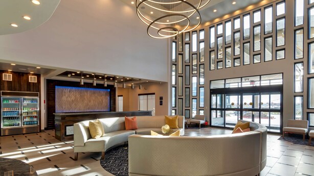A spacious lobby with a large seating area, a television, and a refrigerator stocked with beverages. - Best Western Premier Liberty Inn & Suites (Liberty)