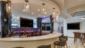 A modern bar area with a curved counter, bar stools, and a large flat-screen TV. - Best Western Premier Liberty Inn & Suites (Liberty)