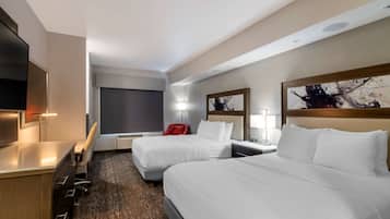 Habitación de hotel con dos camas, un escritorio, un televisor y obras de arte en las paredes.
