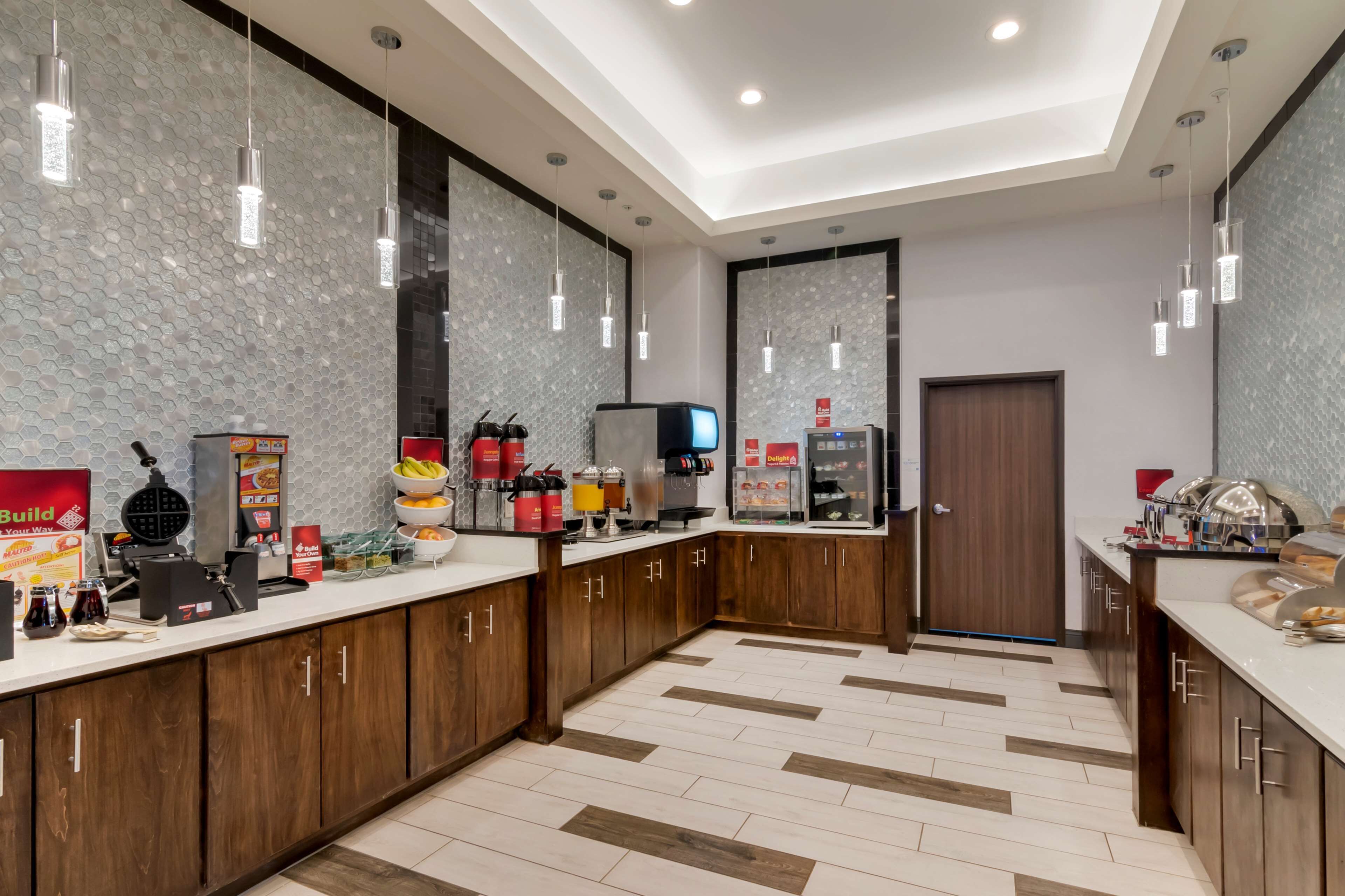 A modern kitchen with wooden cabinets, a white countertop, and hanging pendant lights.