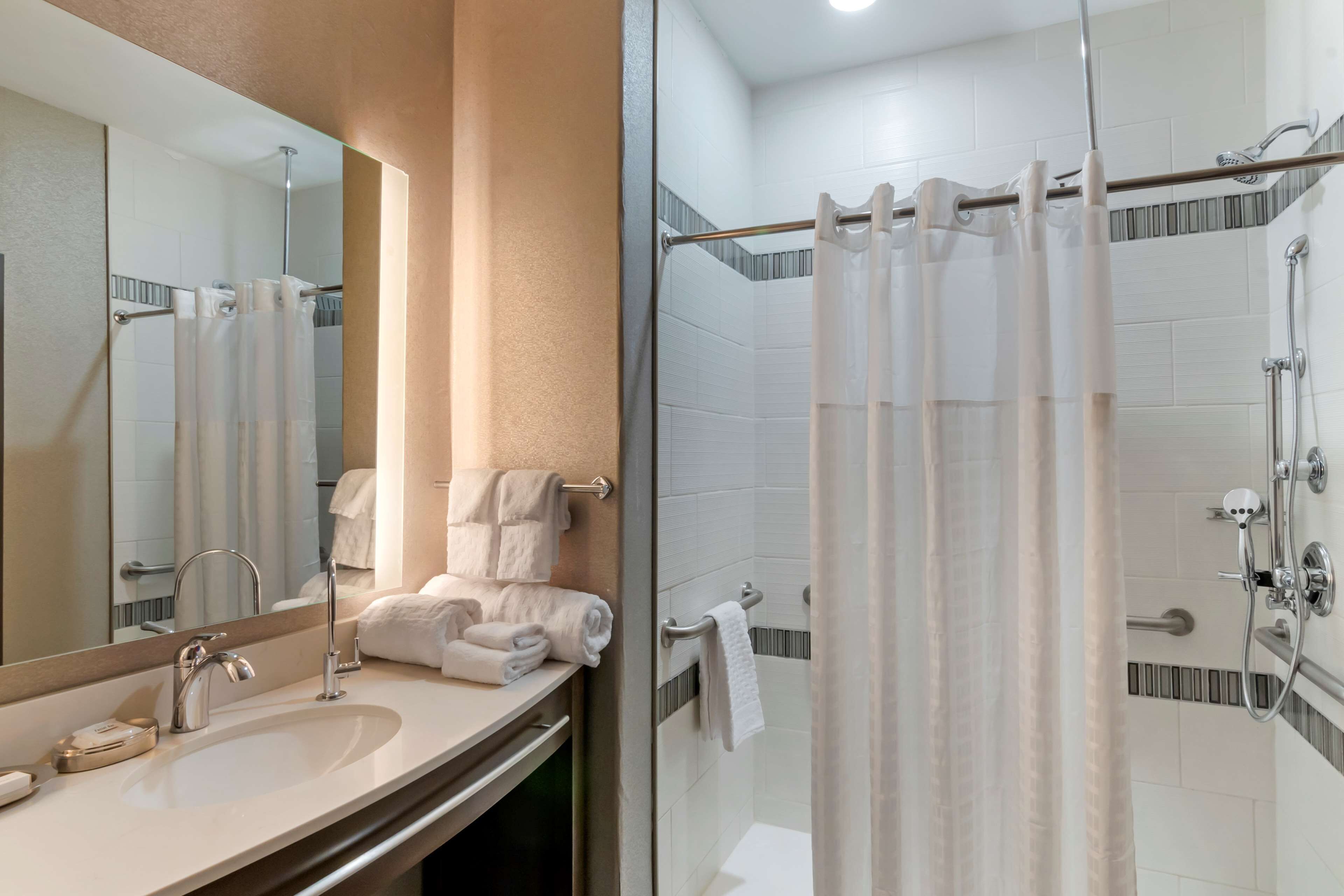Une salle de bain équipée d’un lavabo, d’un miroir, d’un porte-serviettes et d’une zone douche.