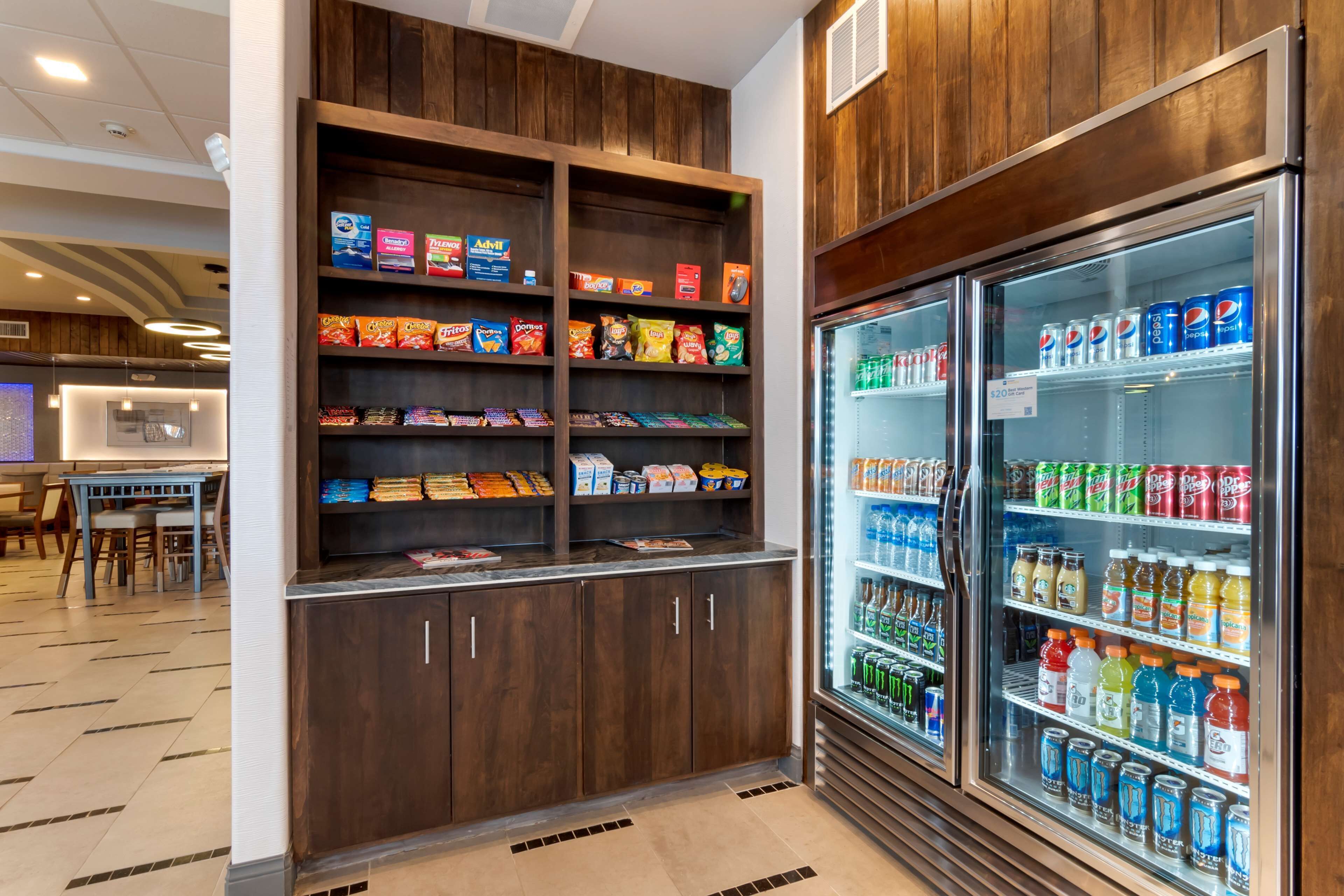 Zona de exhibición de aperitivos y bebidas, con estantes llenos de diferentes opciones y una sección refrigerada con bebidas embotelladas.