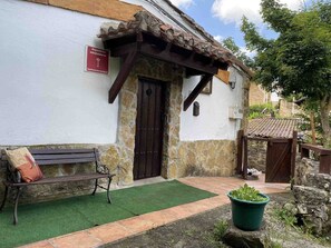 Un edificio rústico con fachada de piedra, puerta de madera y un banco en el exterior.