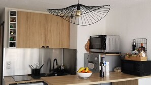 Kompakti keittiö, jossa on pesukone, mikroaaltouuni ja pesuallas. Työtasolla on jakkaroita ja sen yläpuolella riippuvalainen valaisin.