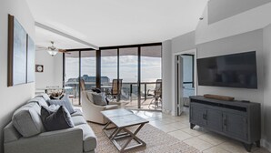Una sala moderna con sofá, mesa de centro y televisor, que cuenta con un balcón con vistas a la ciudad.