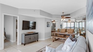 Un salón espacioso con una amplia televisión de pantalla plana, una mesa de comedor de madera y un sofá cómodo.