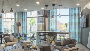 A modern interior with seating, tables, and a bar area, featuring large windows and natural light. - Holiday Inn - the niu, Seven Dusseldorf Ost by IHG (Düsseldorf)