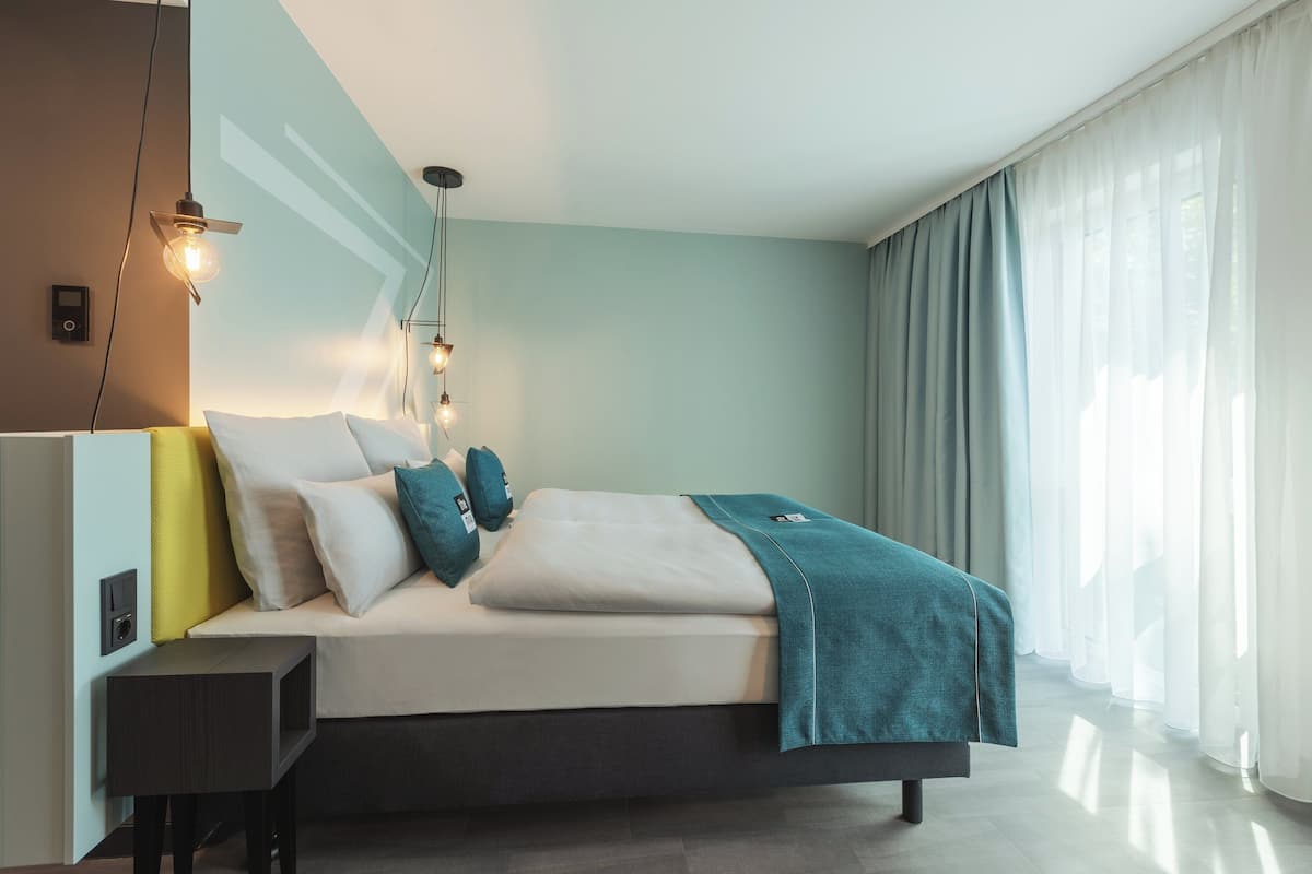 A modern bedroom with a bed, bedside table, and a hanging light fixture.