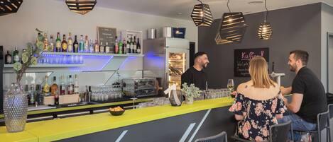 A bar area with a counter, bar stools, and a variety of bottles and glasses.