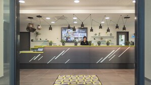 A reception area with a modern design, featuring a reception desk, multiple pendant lights, and a wall display. - Holiday Inn - the niu, Seven Dusseldorf Ost by IHG (Düsseldorf)