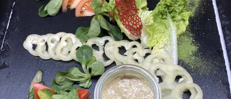 A salad with various vegetables and a jar of dressing on a slate board.