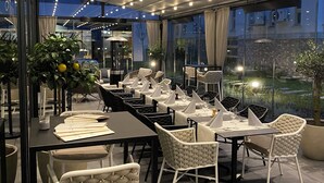 Un restaurante con mesas dispuestas para comer, terraza y vistas panorámicas de la ciudad.