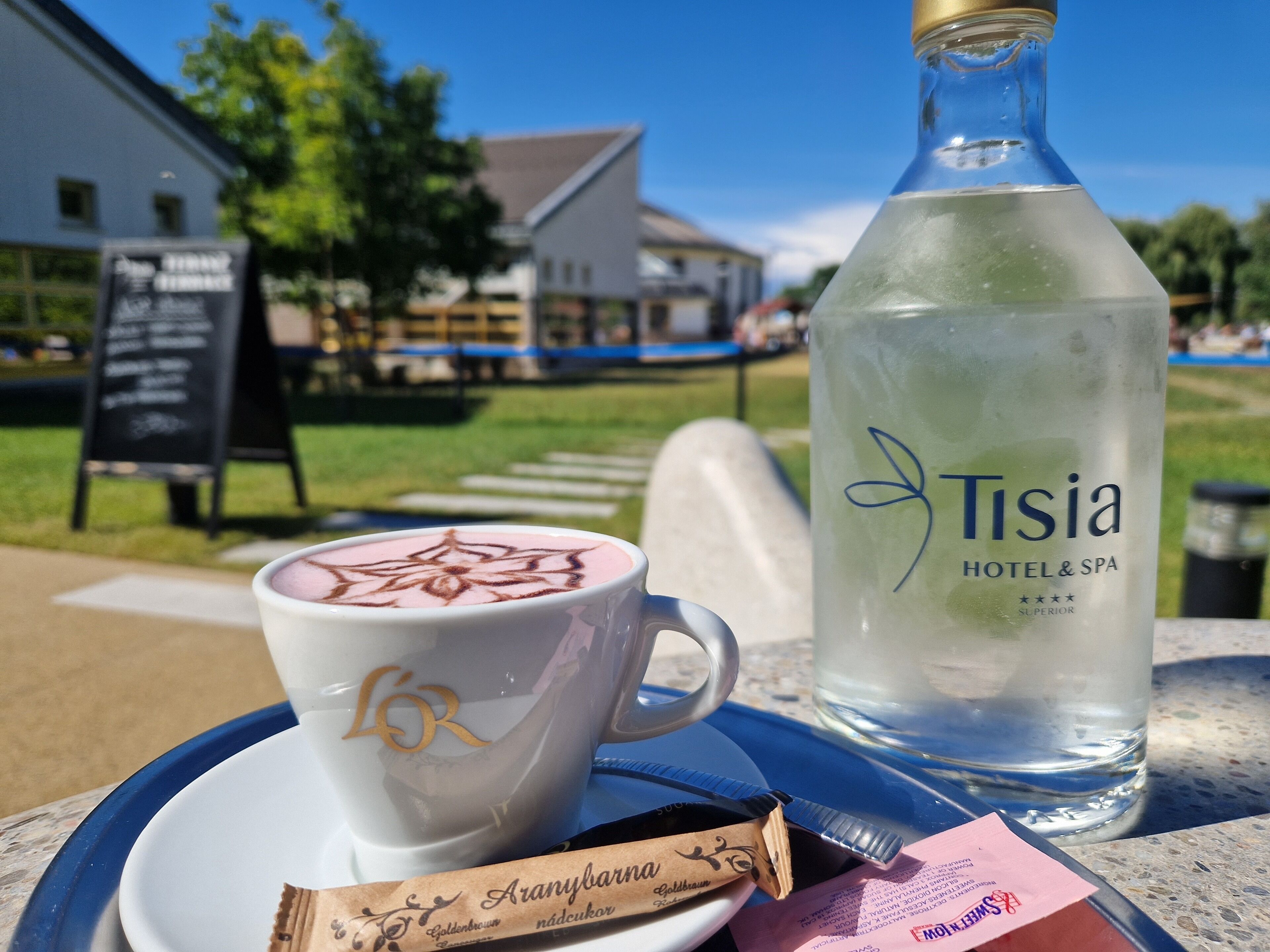 Ein Tisch mit einer Kaffeetasse, einer Wasserflasche und einer Schokoladenriegel.