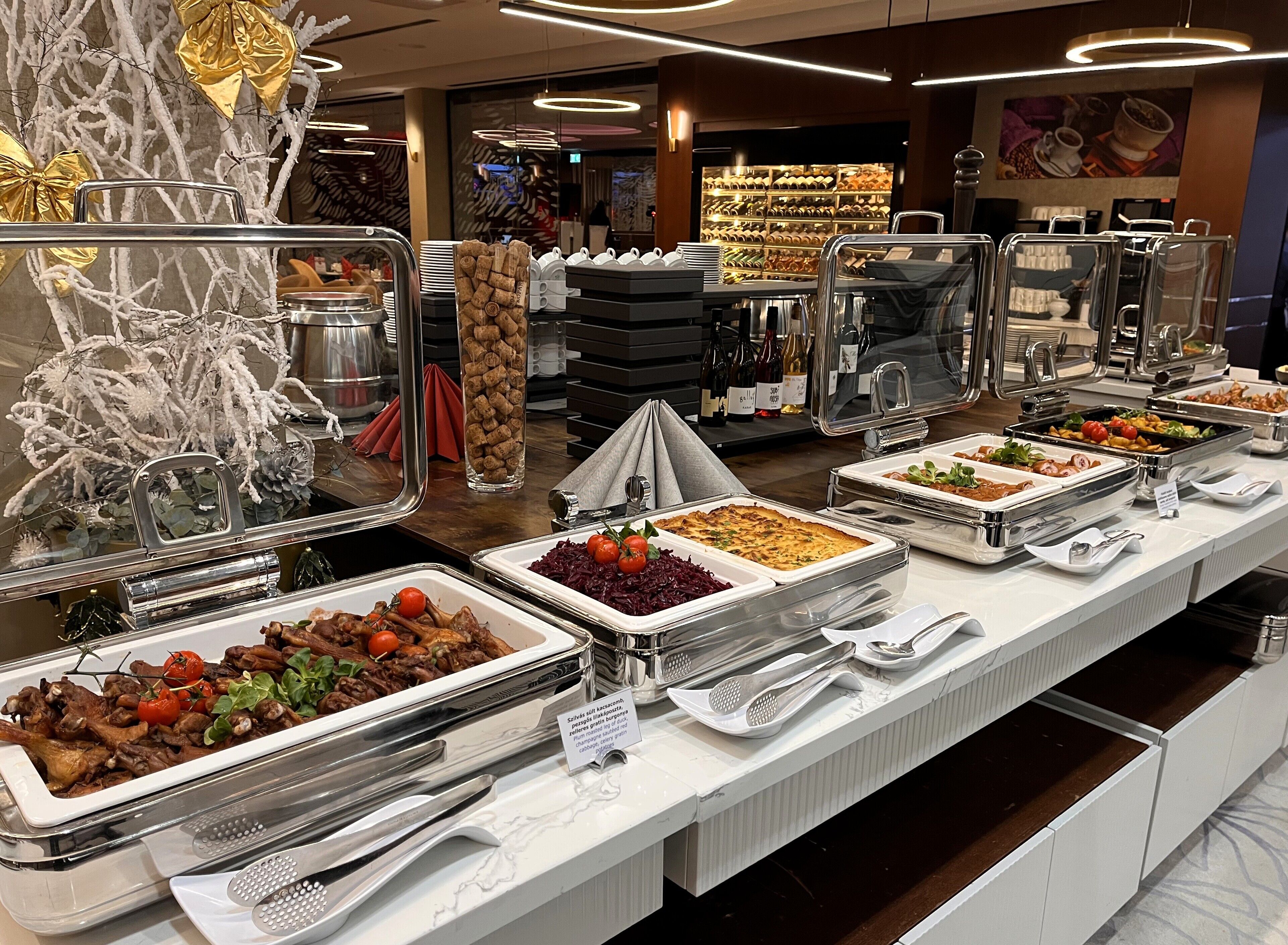 A buffet with various food options, including salads, meats, and desserts, in a well-lit, modern setting.