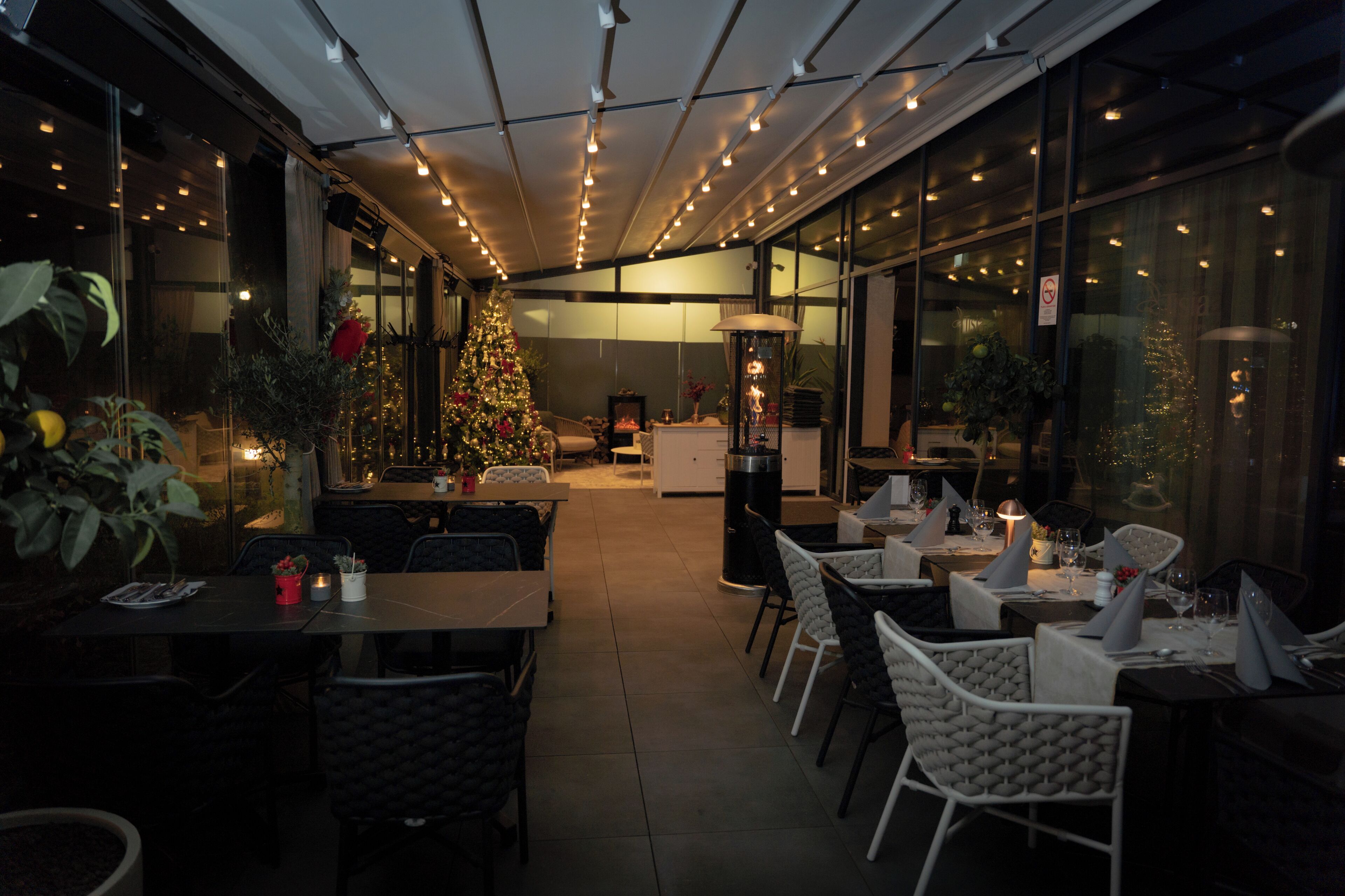 Un comedor interior con mesas y sillas, un árbol de Navidad y un ventanal grande.