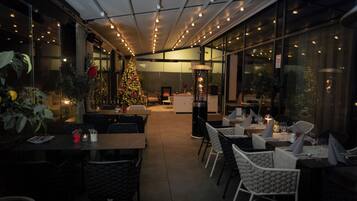 Un comedor interior con mesas y sillas, un árbol de Navidad y un ventanal grande.