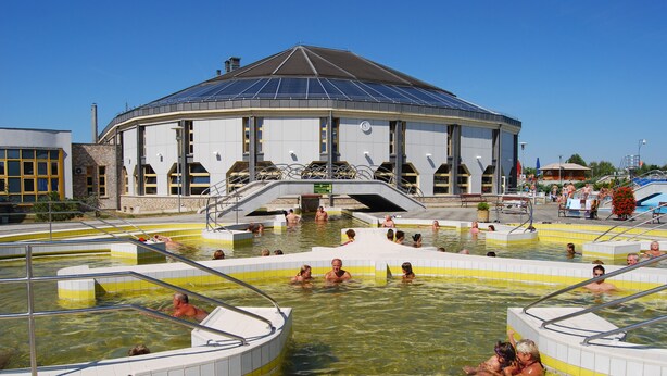 Un edificio grande con techo abovedado y varias piscinas.